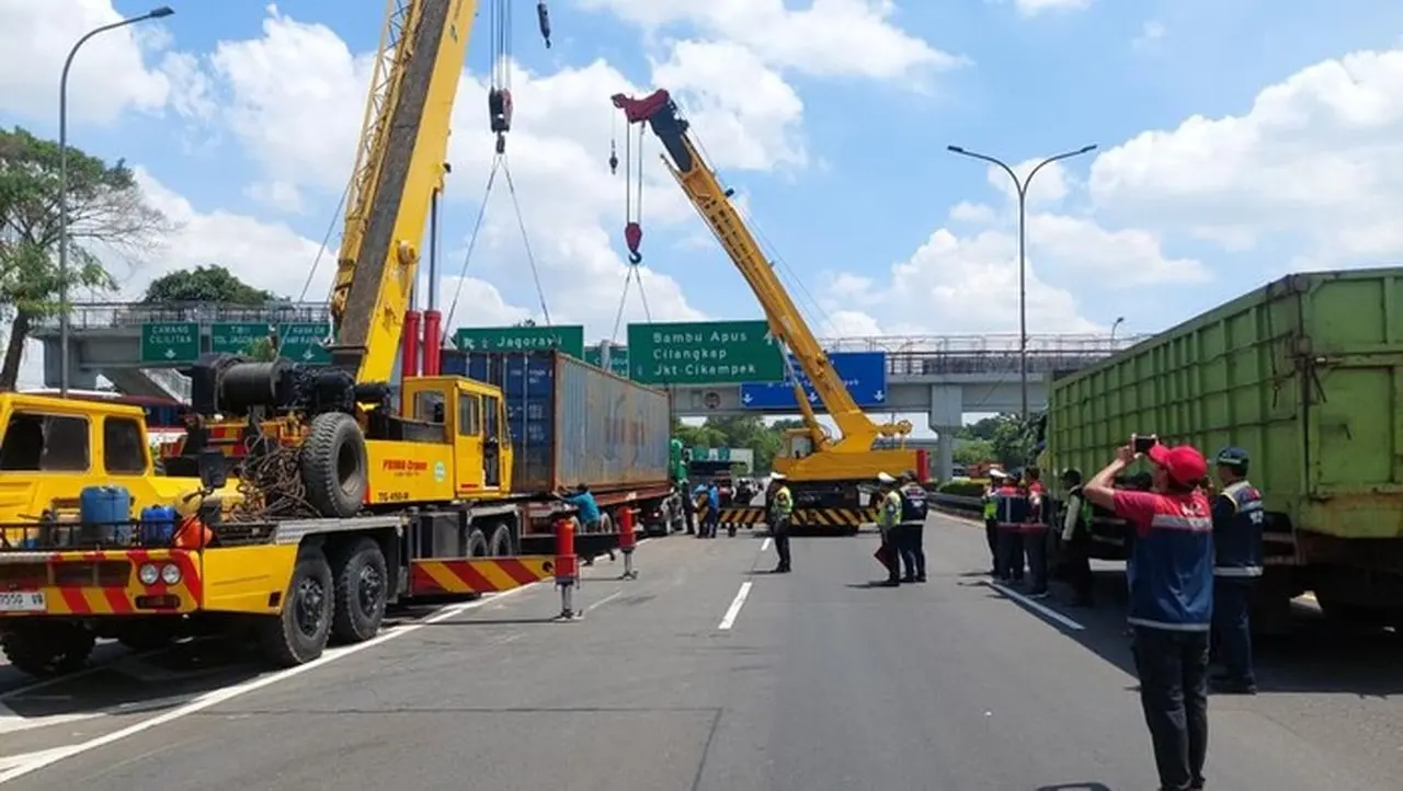 Polisi Mengevakuasi Truk Kontainer Terguling Di Tol Jorr Dengan Dua Alat Berat. (dok.tmc Polda Metro Jaya)