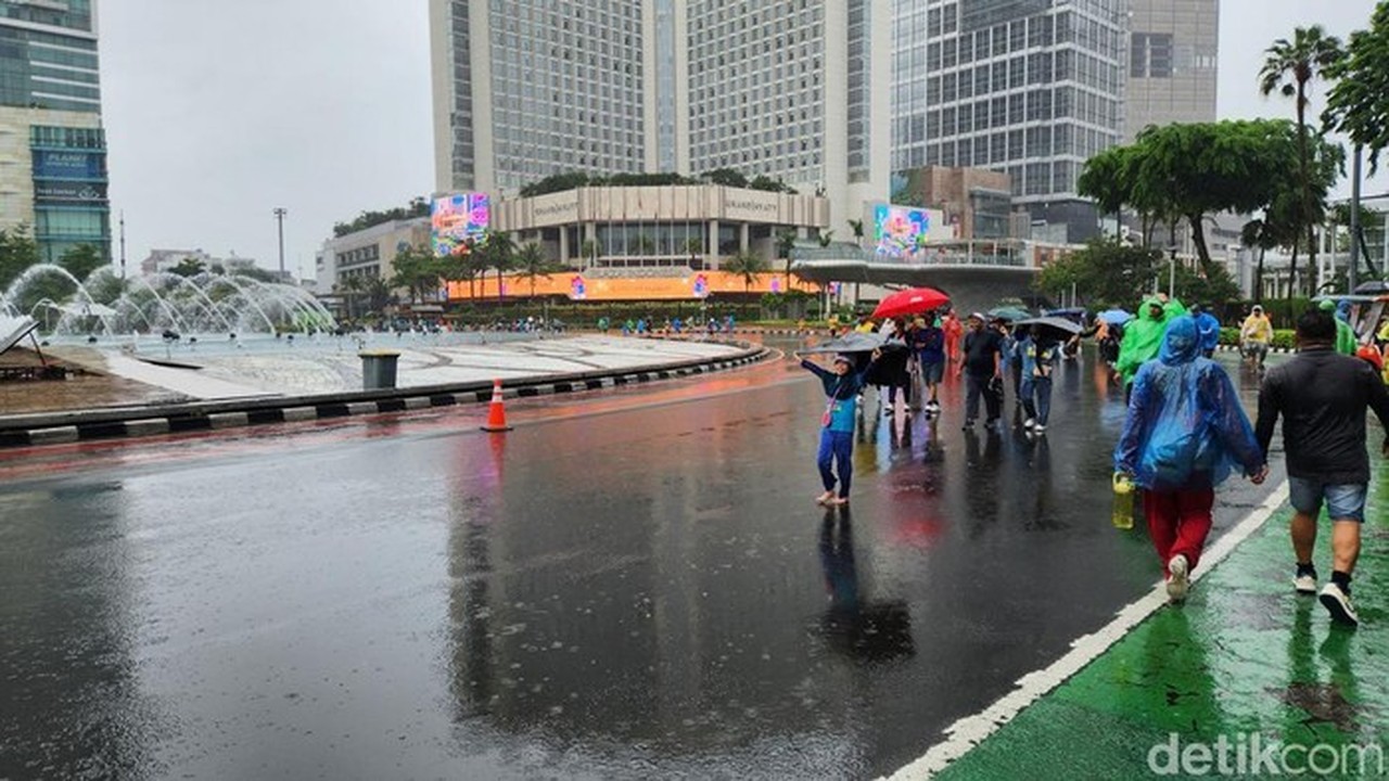 Warga Tetap Berolahraga di CFD Bundaran HI Meski Diguyur Hujan Lebat